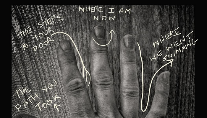 A hand photographed in black and white with text drawn on top of the image. 