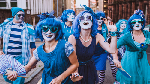 A group of performers, all dressed in bright blue and wearing blue wigs, at Merchant City Festival
