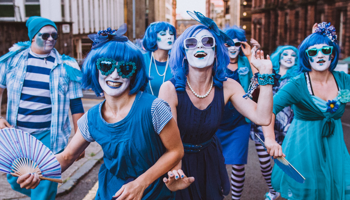 A group of performers, all dressed in bright blue and wearing blue wigs, at Merchant City Festival
