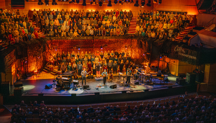Balcony shot of Karine Polwart performing on stage at Glasgow Royal Concert Hall with musicians and a choir.
