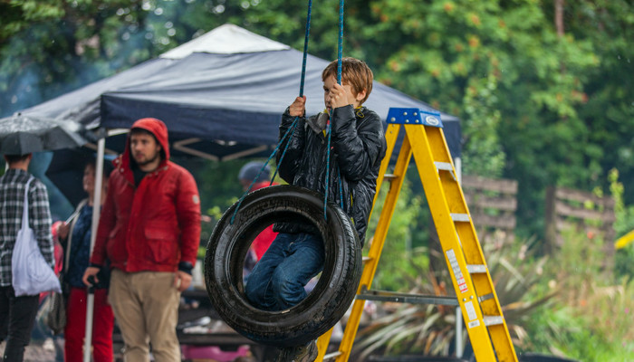 A young child playing on a tyre swing at Baltic Street Adventure Playground in Glasgow.