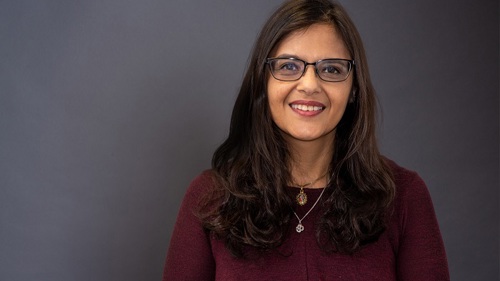 A person with long hair wearing glasses and smiling