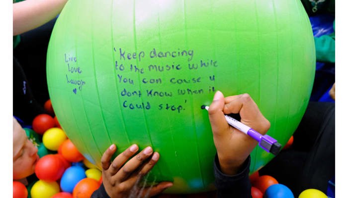 A child write a message on a green yoga ball it reads" Keep dancing to the music while you can, ‘cause you don’t know when it /could stop"