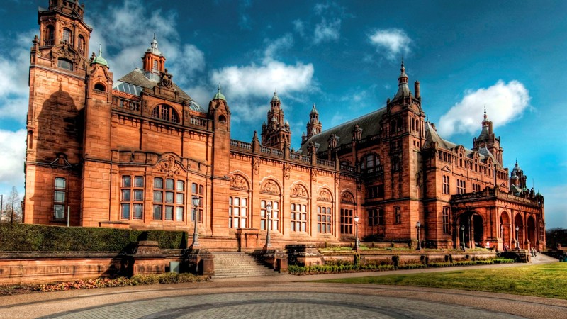 The exterior of Kelvingrove Art Gallery and Museum which is a large red sandstone building with multiple towers and arched windows