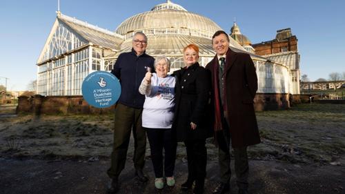 Four people standing outside a large glass winter garden structure