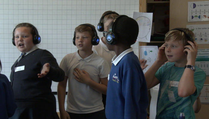 A group of school children dance to music. 