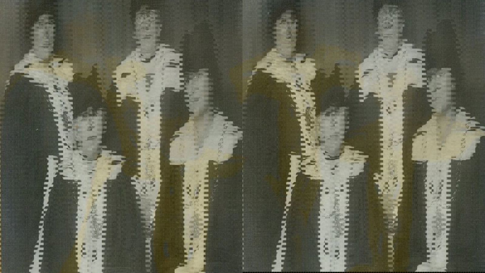 Black and white photo of Mary barbour sitting end left with three other people wearing their ceremonial robes which includes a black hat, white fluffy collar, lapels and cuffs and a large medallion.