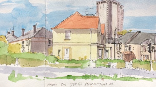 A watercolour. The image looks cheery and almost is painted in the style of a countryside scene. It depicts two story houses with a tower block in the background. The building are set against a blue sky and green trees. 