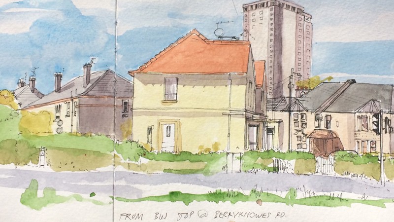 A watercolour. The image looks cheery and almost is painted in the style of a countryside scene. It depicts two story houses with a tower block in the background. The building are set against a blue sky and green trees. 