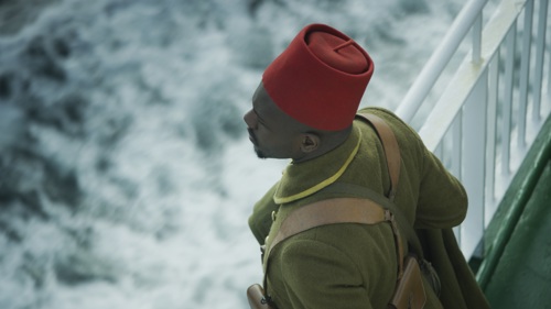 A close up of a soldier from above, gazing out to see from a ship's deck