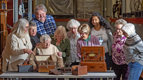 Photograph showing a group of people looking at and discussing a handling box.