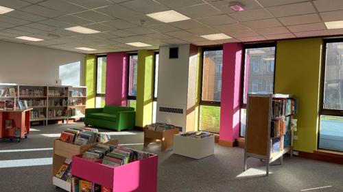 An open plan library space with colourful seating and bookshelves