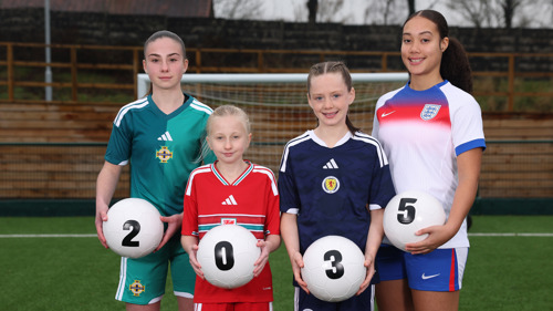 Four female footballers wearing green, red, blue and white tops hold footballs which spell out '2035'
