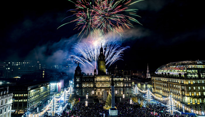 Christmas lights are lit up in Glasgow's George Square as red, green and blue fireworks are set off above Glasgow City Chambers
