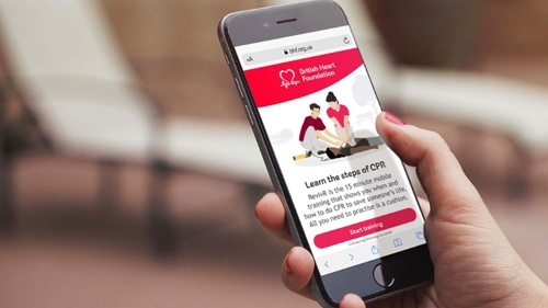 Close up of a mobile phone in a hand showing animated instructions on how to perform CPR