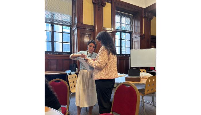 Two people are standing together. They are discussing something, being held in their hands