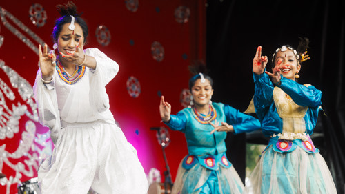 Three dancers perform wearing white and light blue outfits