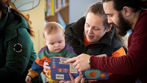 Parents showing their young child a book in the library