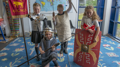 Four children dressed in costumes and holding replica weapons, take part in a Romans workshop at Glasgow Museums Resource Centre