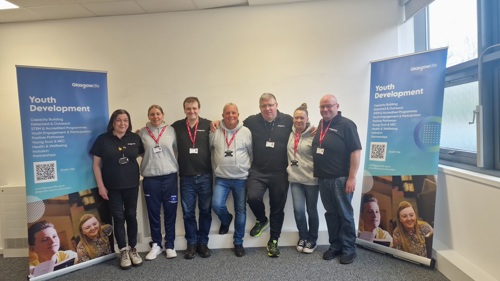 A group of 7 people gathered for a group photo between two banners that read Youth Development