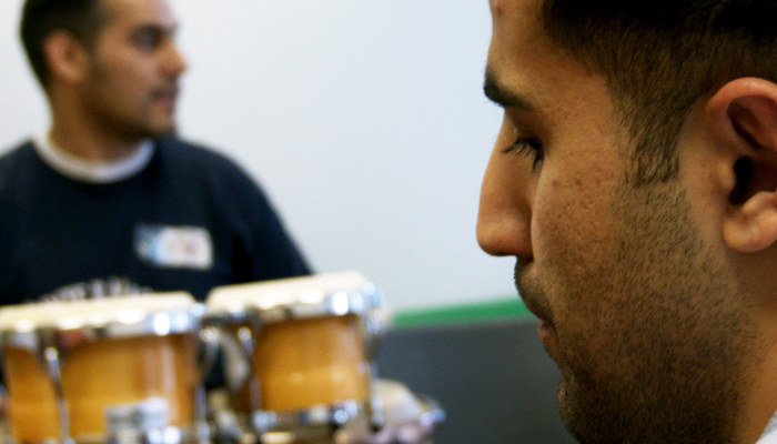 Two people, rehearse music one has hand held drums.