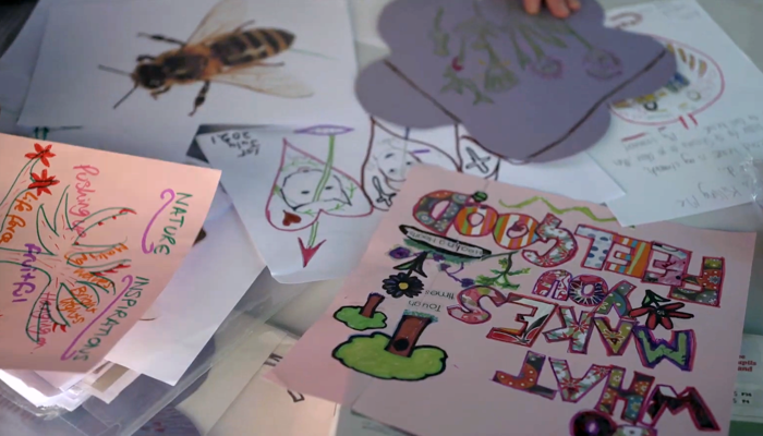 Spread across a table are drawing and letters created by local community groups they are brightly coloured and who images of nature. 