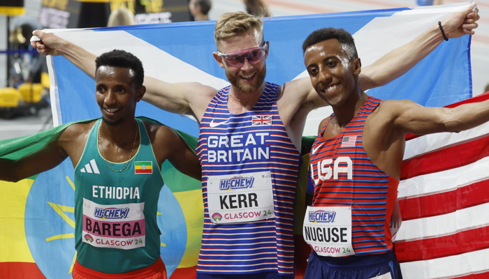 Josh Kerr holding the Scotland flag after winning gold in the 3000 metres at the World Athletics Indoor Championships in Glasgow. He is alongside silver medallist Yared Nuguse from the USA and Selemon Barega from Ethiopia who won bronze.
