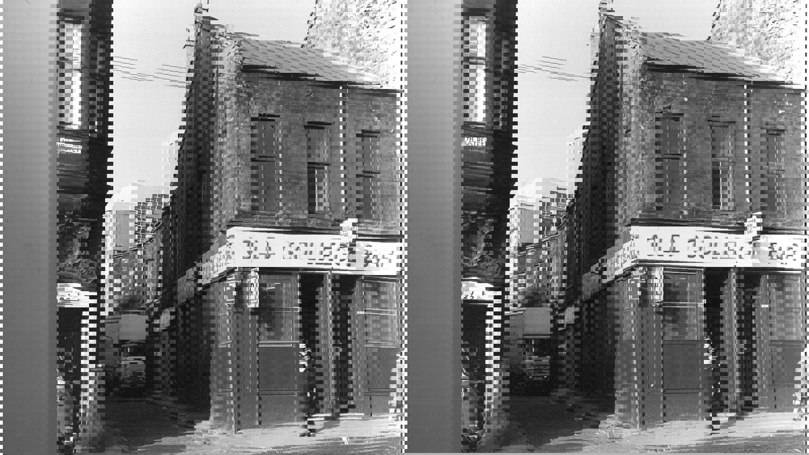 A black and white photograph of a pub in Glasgow called Old College Bar which is situated on a main road with a lane on it's right hand side. There is a parked white lorry in the lane and people walking on the pavement outside the pub.