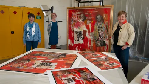 three people standing around a canvas of a painting
