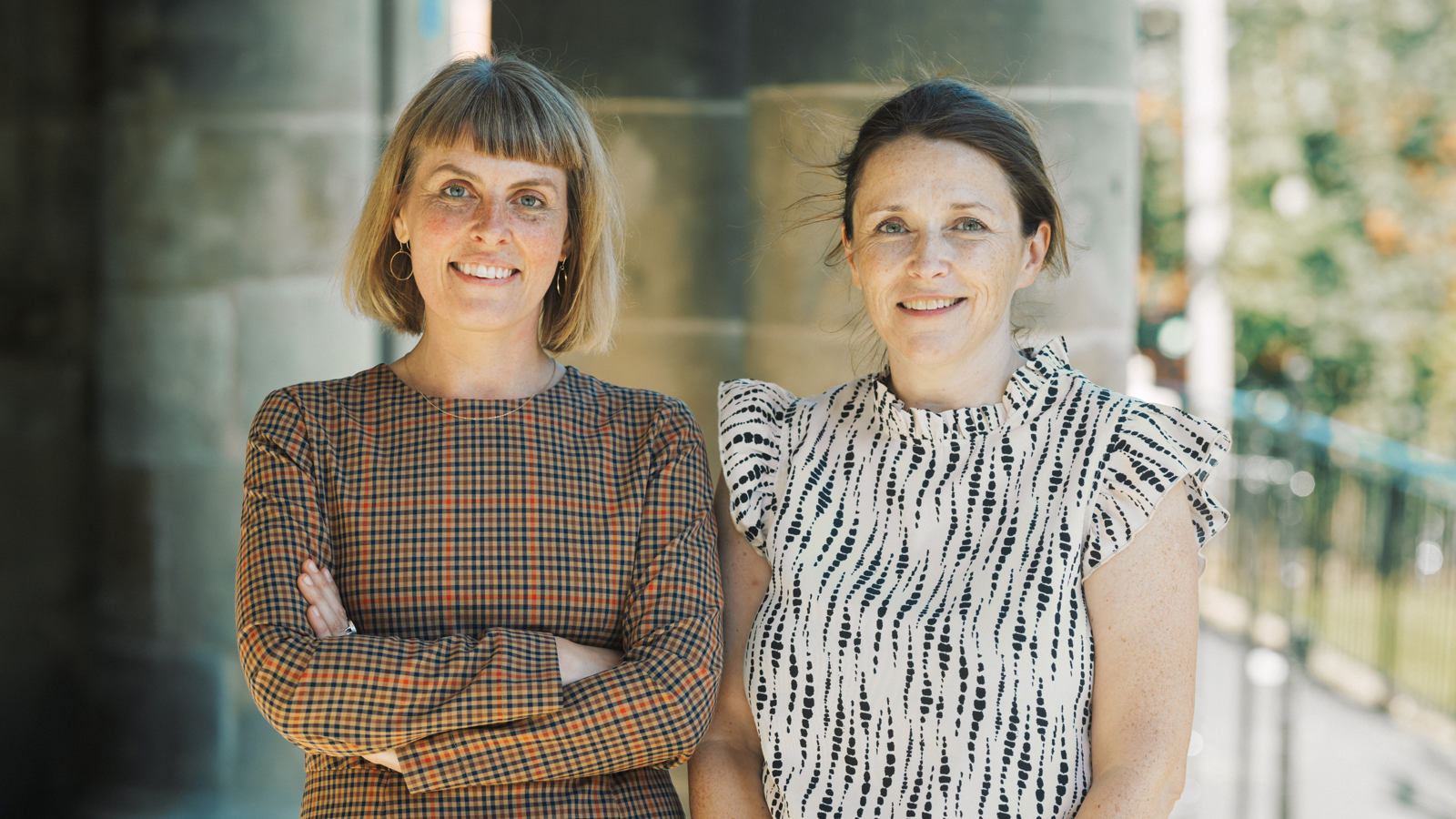 Two people standing in front of a library building pillar
