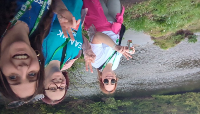 A group of three people on a charity walk alongside a river
