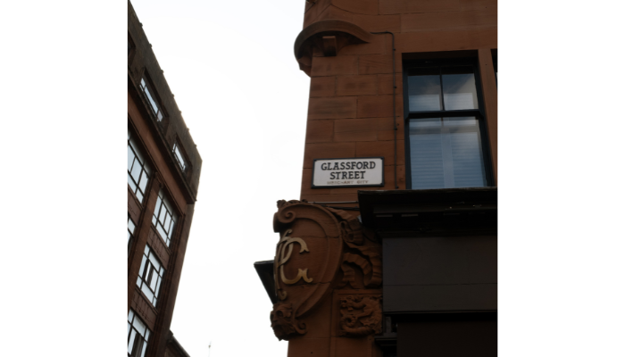 red sandstone building with street sign with the word Glassford Street