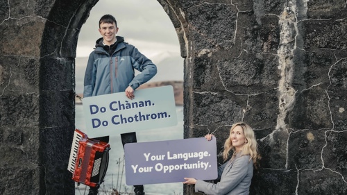 Two people posing for a photo at a castle ruin. There is an accordion on the ground next to them