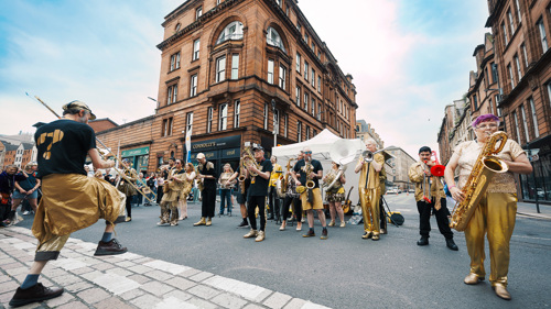 A brass band dressed in gold performs on a street
