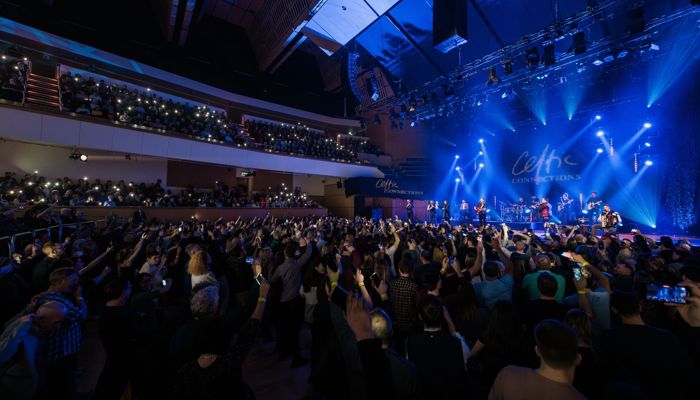 A large crowd standing at a music concert in a concert hall