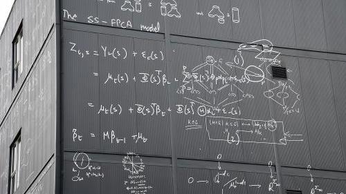 Close up of exterior of modern grey university building with white calculations painted on the walls