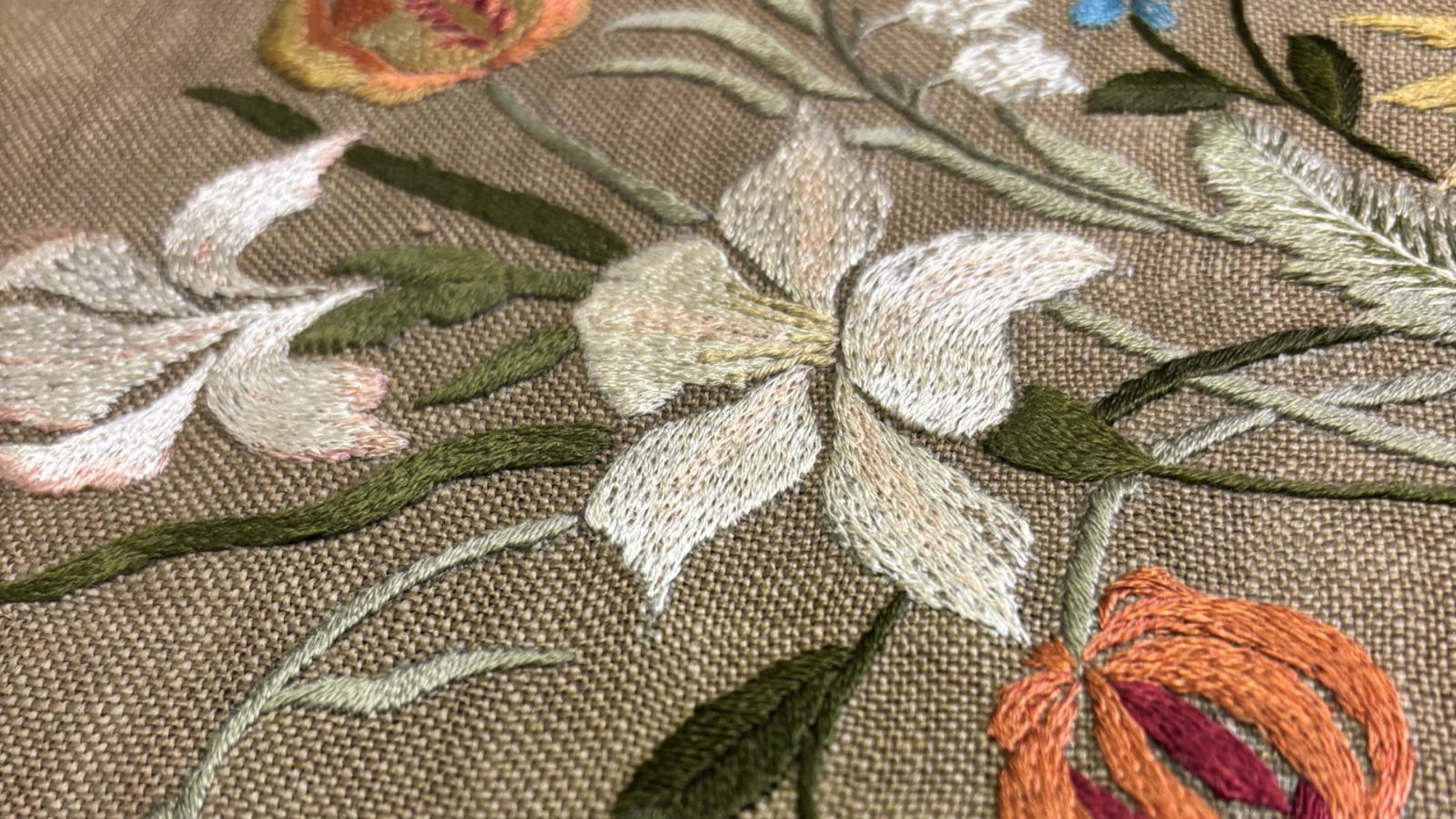 CLOSE UP OF AN EMBOIDERED BOOK COVER FEATURING FLOWERS