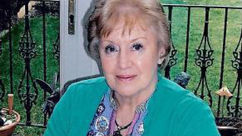 A photo of Moira Stewart, wearing a green cardigan, sitting outside on a clear day.
