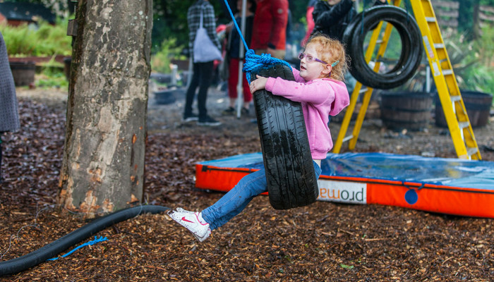 A young child playing on a tyre swing at Baltic Street Adventure Playground in Glasgow.
